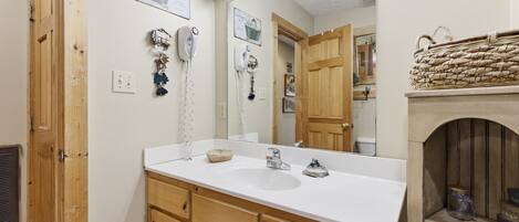 A bathroom with a wooden vanity, a large mirror, and a vanity light.
