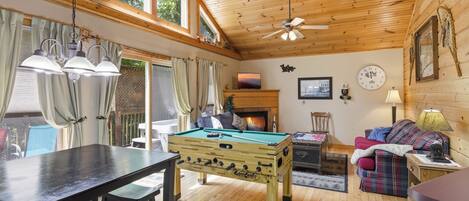 A cozy indoor space with a pool table, a sofa, and a fireplace.