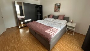 Ein Schlafzimmer mit Bett, Nachttischen, einem Kleiderschrank und einem Spiegel.