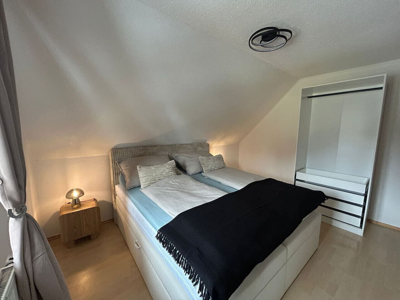 Une chambre à coucher comprenant un lit, une table de chevet, une lampe et une armoire.
