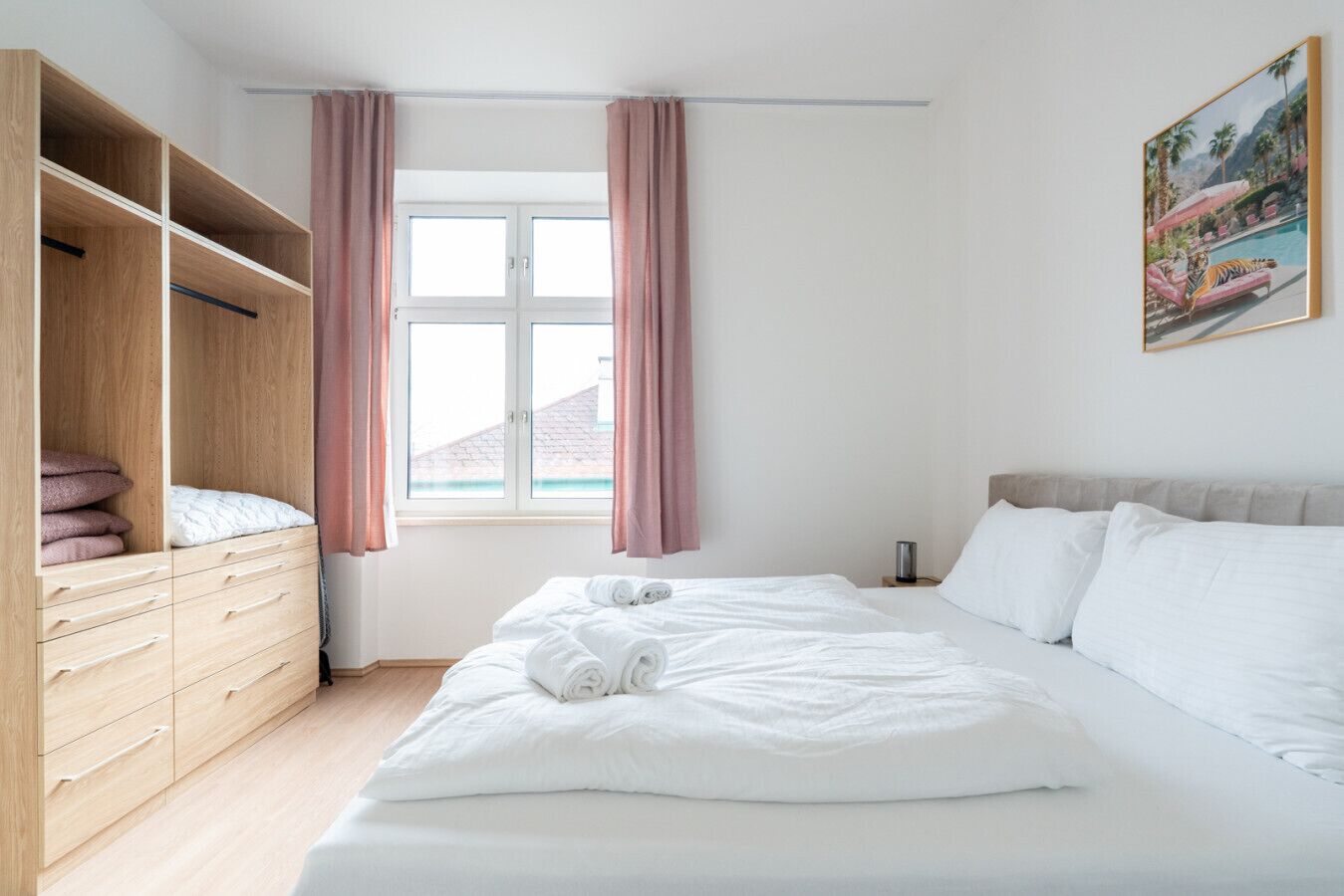 Um quarto com uma cama, um guarda-roupa, uma janela com cortinas e um quadro na parede.