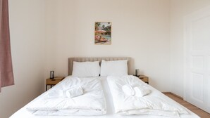 A bedroom with a bed, two bedside tables, a nightstand, a wall-mounted picture, and a door. - Faraway Homes Studio Klosterneuburg #5 (Klosterneuburg)