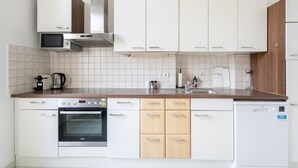 A modern kitchen with white cabinets, a stainless steel range hood, a microwave, a toaster, a coffee maker, and a dishwasher. - Faraway Homes Studio Klosterneuburg #5 (Klosterneuburg)