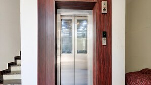 Un ascensore con un pannello di controllo, una scala e un letto con biancheria decorata.