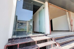 Une entrée moderne avec une porte en verre, un escalier en métal et une main courante métallique.