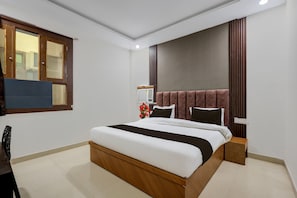 Een moderne hotelkamer met een groot bed, een houten hoofdbord, een raam met zonwering en een klein nachtkastje.
