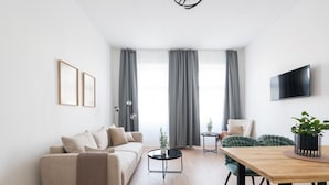 Un salon moderne avec un canapé, une table à manger, un téléviseur et une plante.