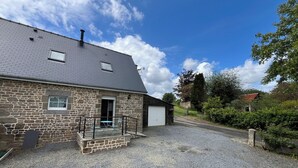 Ein Steinhaus mit Kiesweg, Garage und einer kleinen Außen-Sitzgelegenheit.