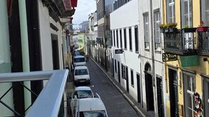Una stretta via fiancheggiata da edifici, cielo azzurro e auto parcheggiate.