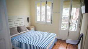Una camera da letto con un letto, un comodino, una sedia, una finestra e una porta.