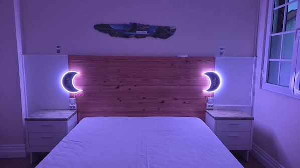 A bedroom with a wooden headboard, two bedside tables, a bed, and a wall-mounted artwork. - AP200 (Ponta Delgada)