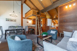 Ein Loft-Wohnraum mit Essbereich, einer Schlafgalerie mit Holzleiter und einer Küchenzeile.