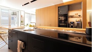 Een moderne keuken met een groot eiland, een ingebouwde oven en een koelkast.