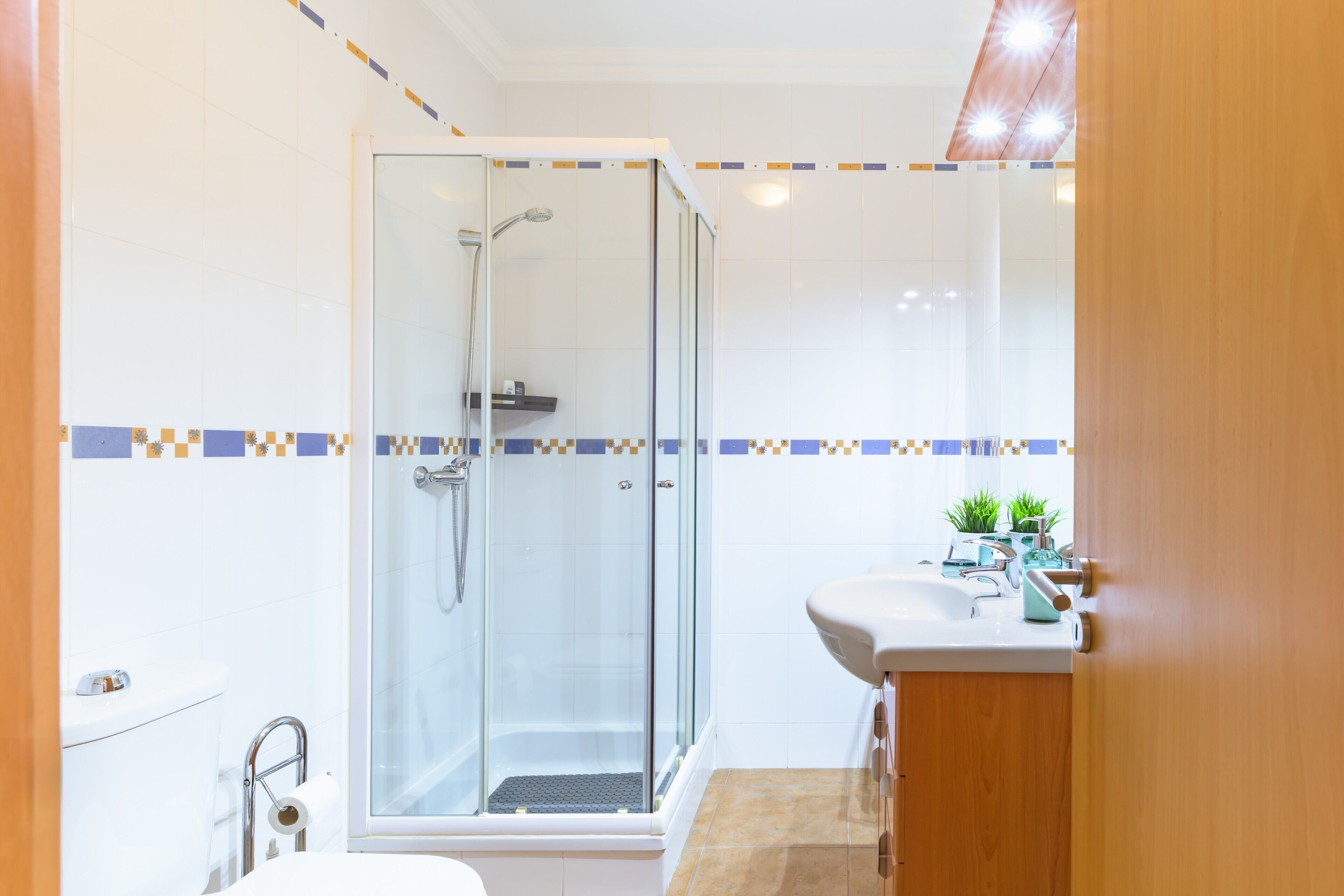 A bathroom with a glass-enclosed shower, a toilet, and a sink with a mirror.