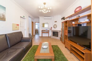 Ein Wohnzimmer mit einer Ledersofa, einem Holztisch, einem Flachbildfernseher, einem Kamin und einem Spiegel an der Wand.