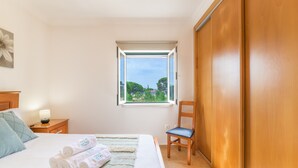 Una camera da letto con un letto, una finestra, una sedia, un comodino e un armadio.