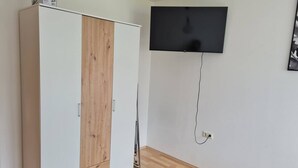 Quarto com guarda-roupa, televisão montada e tapete estampado.