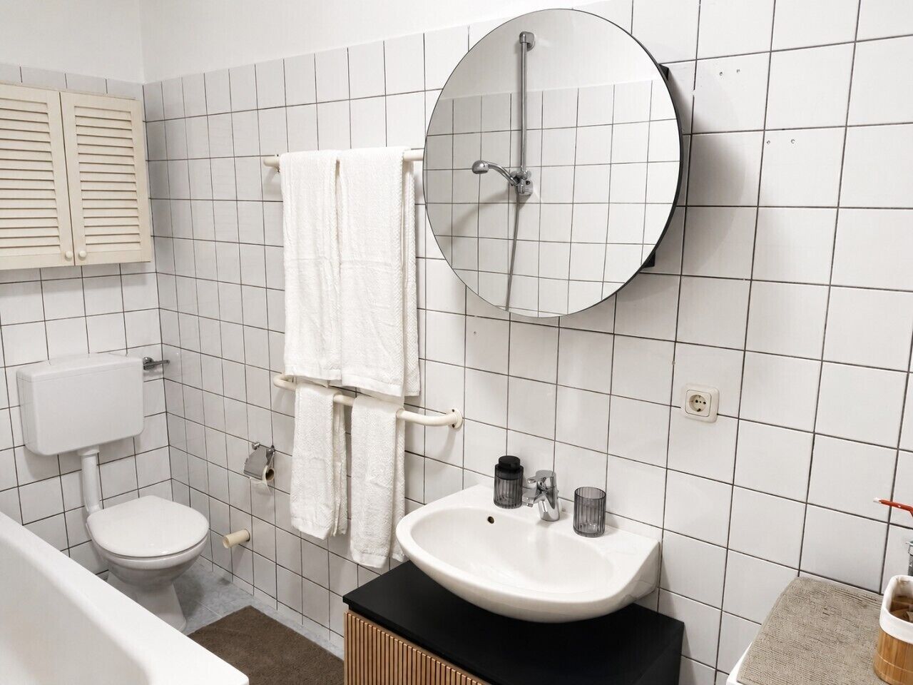 Une salle de bain équipée de toilettes, d’un lavabo, d’un miroir et d’un porte-serviettes.
