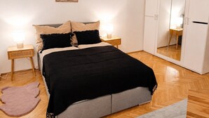 A bedroom with a bed, bedside lamps, a mirror, and a wardrobe. - Faraway Homes Studio Enns #14 (Enns)