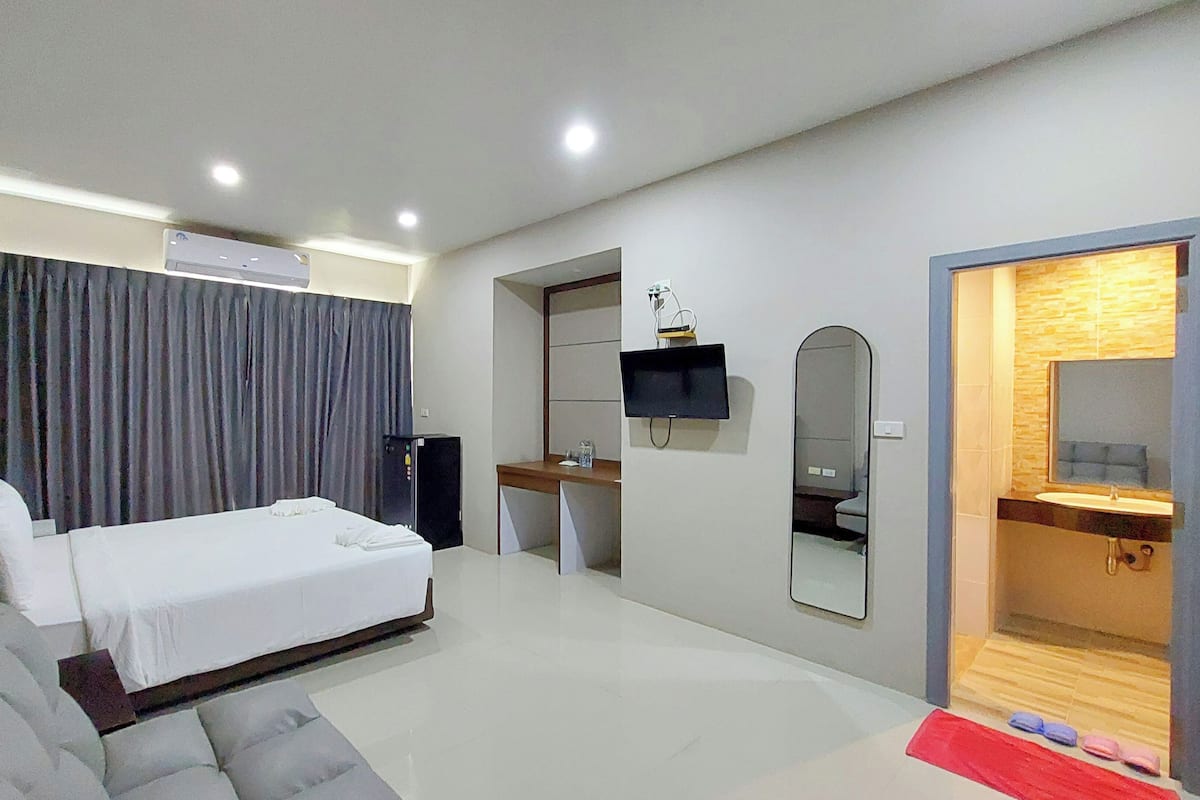 A modern hotel room with a bed, a desk, a TV, and a bathroom.