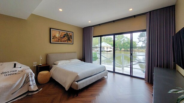 Um quarto com uma cama, uma mesa de cabeceira, um abajur, uma janela grande com cortinas e um quadro na parede.