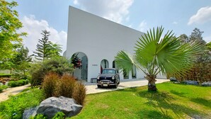 Um edifício moderno com fachada branca, janelas em arco e um carro preto estacionado na frente.