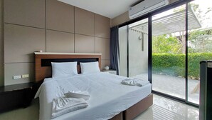 Quarto de hotel moderno com uma cama grande, uma mesa de cabeceira, uma janela com vista para áreas verdes e um ar condicionado.