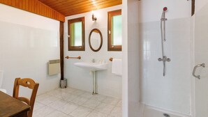 Een badkamer met een wastafel, spiegel, douche en een houten plafond.