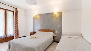 Een hotelkamer met twee bedden, een houten hoofdbord, een nachtkastje en een raam met gordijnen.