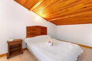 A bedroom with a wooden ceiling, a bed with a white bedspread, a wooden nightstand with a phone, and a wall-mounted light. - Rooms 14 & 15 with Pool (Saint-Pompont)