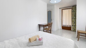 A bedroom with a bed, a desk, a chair, and a door leading to another room. - Guest Rooms 11 & 12 with Pool (Saint-Pompont)