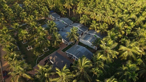 An aerial view of a resort with multiple buildings surrounded by palm trees. - Aarna Coastal Resort (Bhatkal)