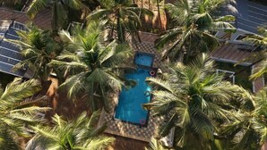 An aerial view of a pool surrounded by palm trees, with a checkered pattern around the pool area. - Aarna Coastal Resort (Bhatkal)