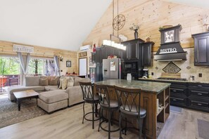 A modern kitchen with a bar area, wooden ceiling, and a sign that reads 'GRATEFUL.' - Cozy NH Log Home | Ski, Hike & Unwind (Littleton)