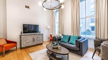 Ein modernes Wohnzimmer mit Flachbildfernseher, einer Couch, einem Couchtisch und einem roten Sessel.