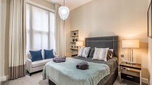 A hotel room with a bed, a sofa, a desk, and a lamp. - Stylish Marylebone Apartment with Modern Soul (London)