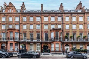 A row of red brick townhouses with multiple stories, each with a front door and a small balcony. - Stylish Marylebone Apartment with Modern Soul (London)