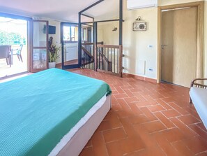 Una habitación con cama, balcón, escalera y puerta.