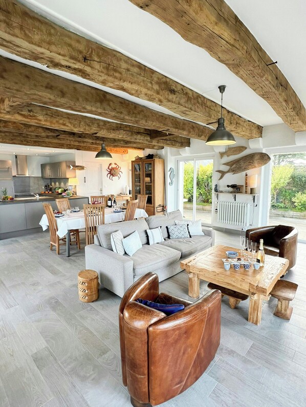 A spacious living area with a high ceiling, a dining area, and a kitchen. - Beach house with 280-degree sea view in Kergoz (Landeda)