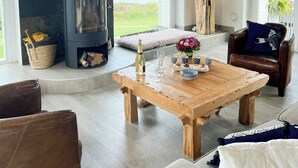 Un salon chaleureux avec une cheminée, une table basse en bois, un fauteuil en cuir et une vue sur la mer.