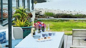 Un espace de restauration en bord de mer, avec une table dressée pour un repas, offrant une vue sur la plage et la mer.