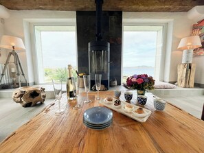 A wooden table with a bottle of champagne, wine glasses, and a tray of pastries. - Beach house with 280-degree sea view in Kergoz (Landeda)
