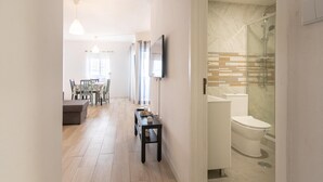 A modern interior with a dining area, a hallway leading to a bathroom with a glass shower enclosure. - 2 bedroom apartment Praia Da Rocha (Portimão)