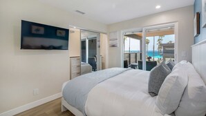 A bedroom with a bed, a TV, a desk, and a view of the ocean. - 3BD/3BA | Ocean Views | 1 Block to the Beach (Oceanside)