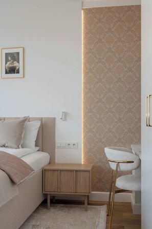 A bedroom with a bed, bedside table, wall-mounted light, and a framed picture.