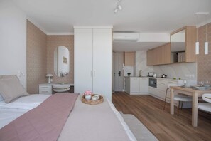 A modern bedroom with a bed, bedside table, and a small sitting area with a table and chairs.