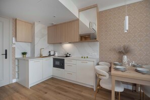 Eine moderne Küche mit weißen Schränken, einer Marmor-Spritzschutzwand und einem Essbereich mit Tisch für vier Personen.