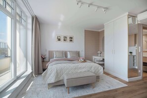 Une chambre moderne avec un grand lit, des tables de chevet, une commode, une fenêtre avec des rideaux et un dressing.