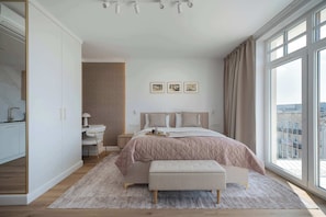 Un dormitorio con cama, mesita de noche y vistas a la ciudad a través de amplias ventanas.