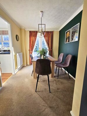 Un espace repas comprenant une table, des chaises, une plante en pot et une vue par la fenêtre.